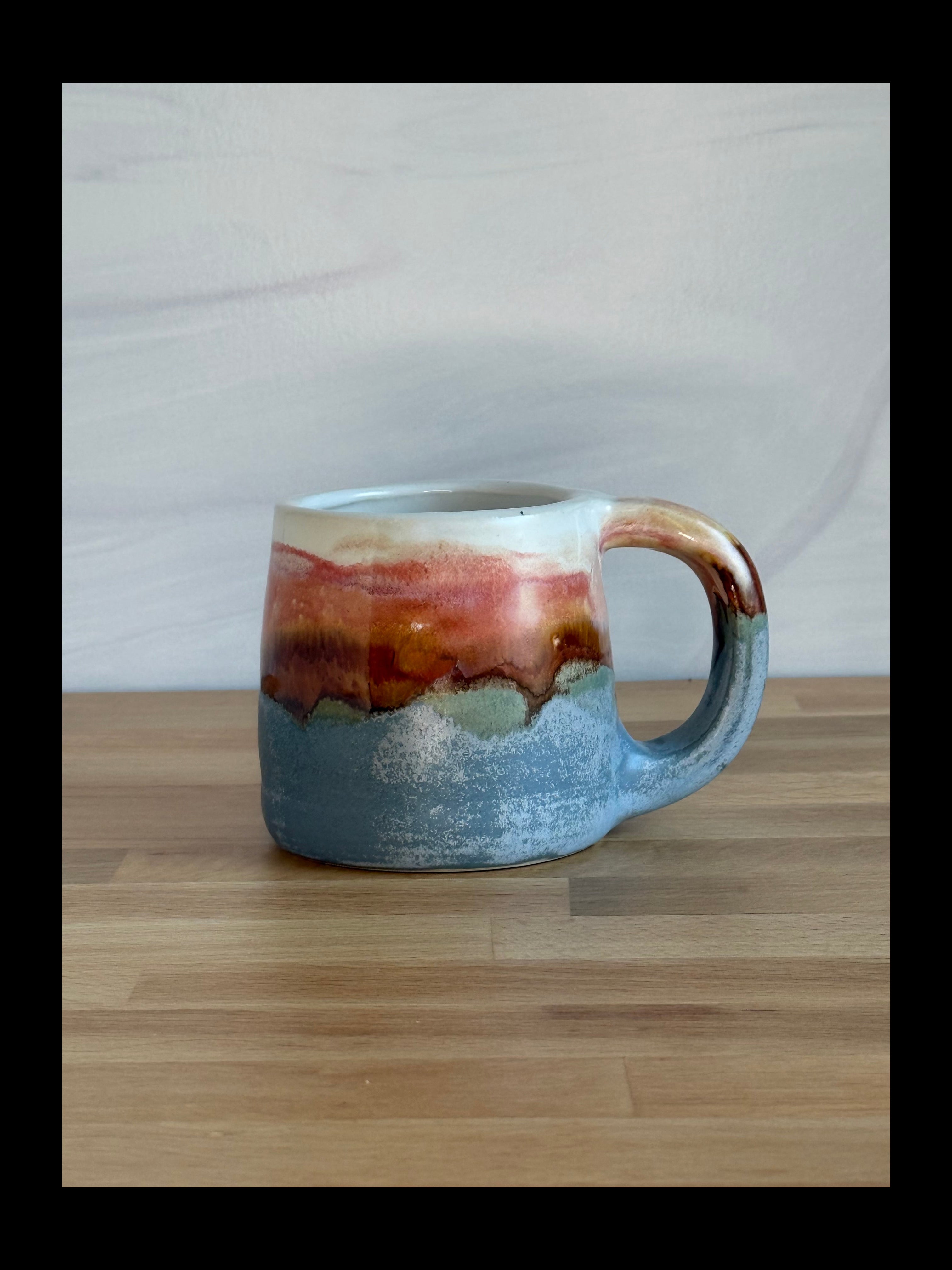 Ceramic mug with a multicolored glaze on a wooden surface