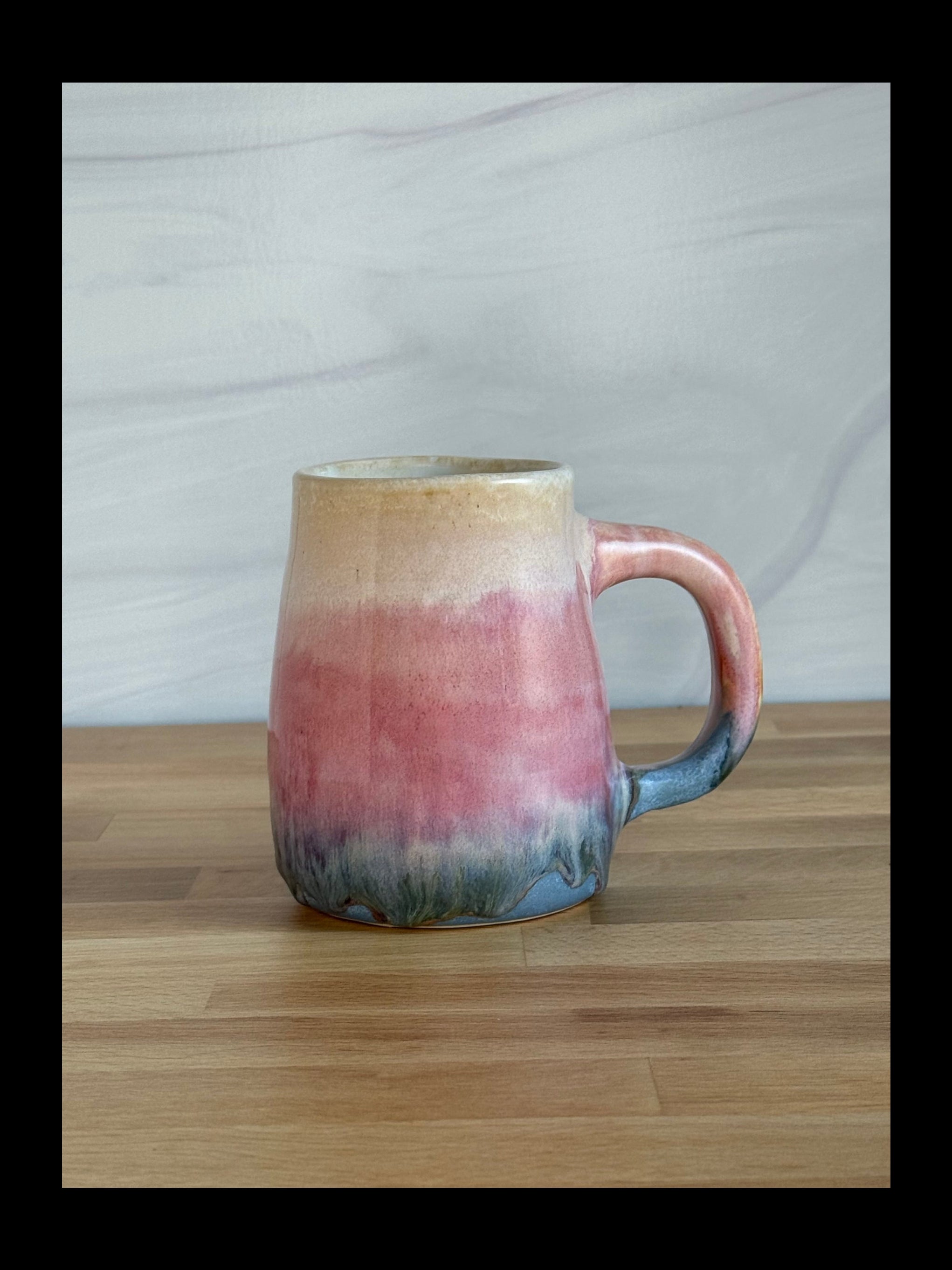 Ceramic mug with gradient color design on a wooden surface